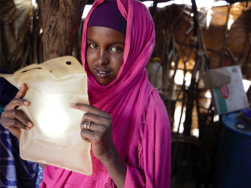 A recipient of ShelterBox aid holding her LuminAid solar light