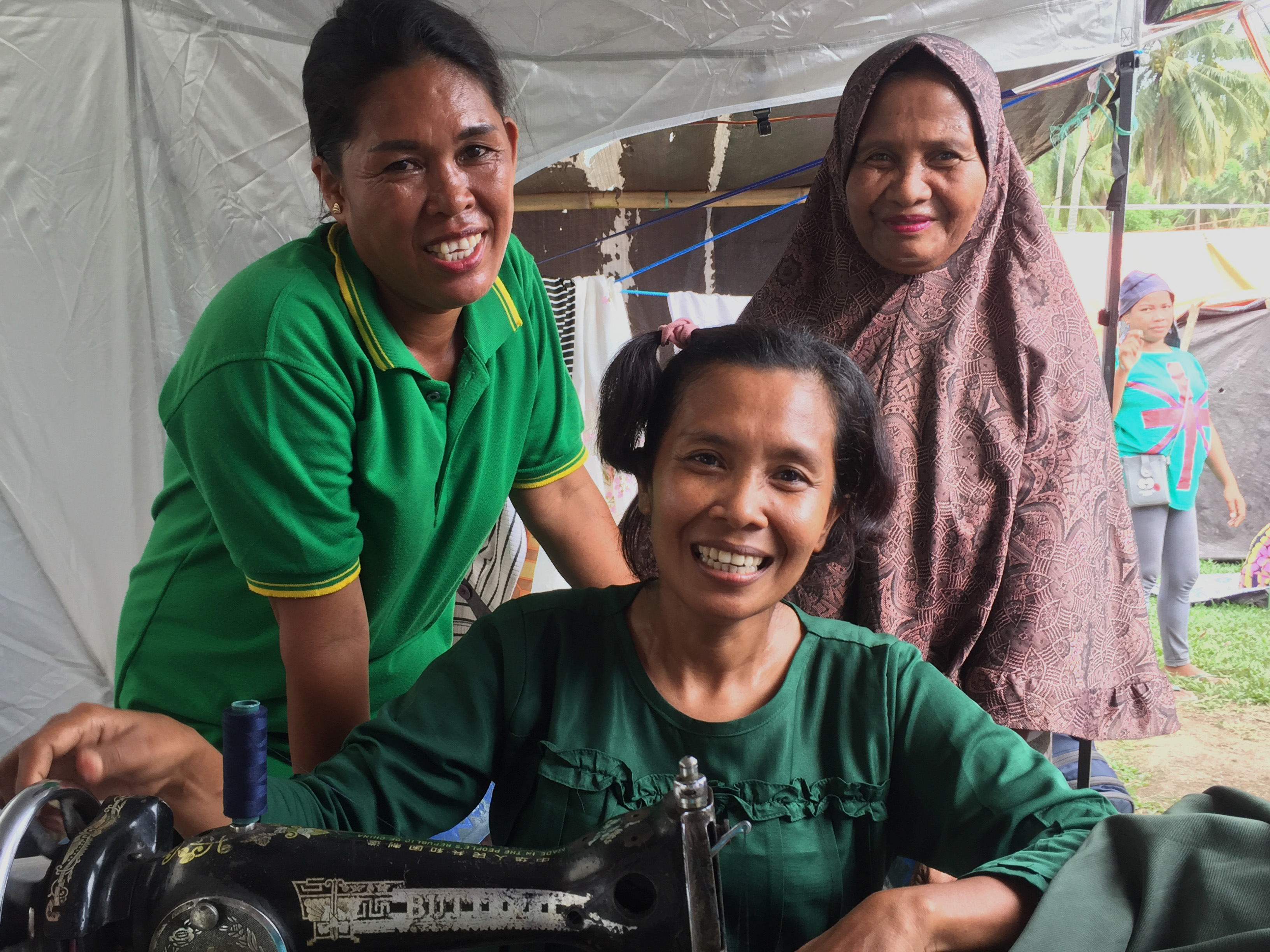 ShelterBox aid in Indonesia A recipient of ShelterBox aid sews within her tent in Indonesia